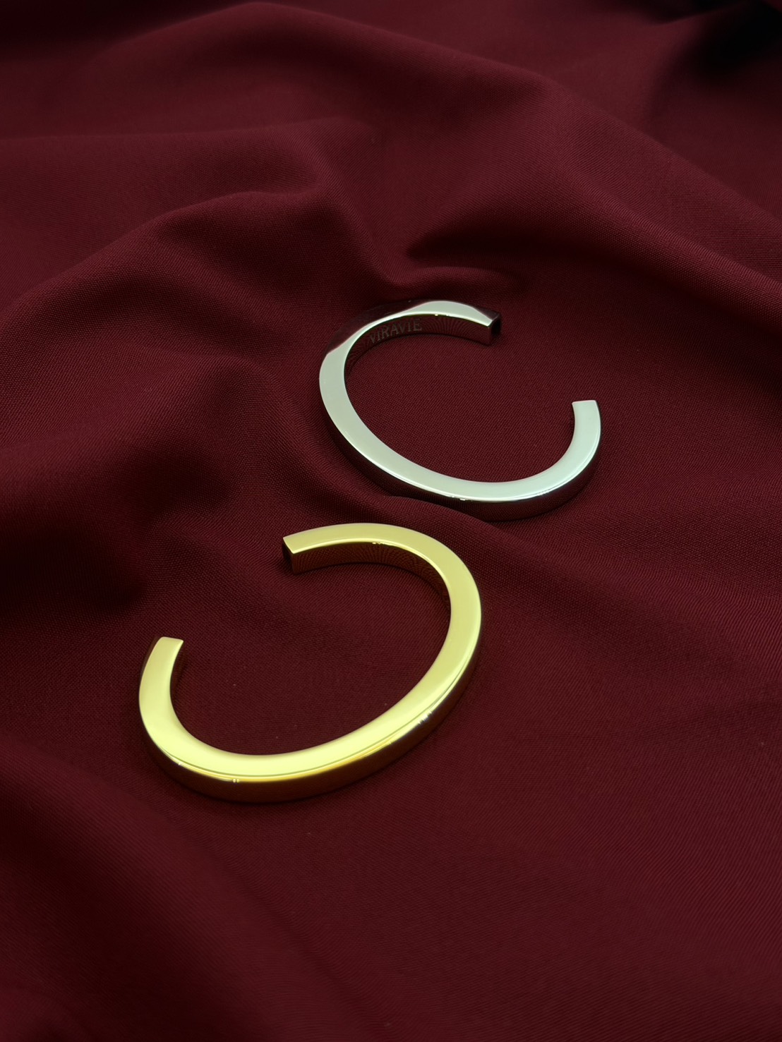 Gold and silver VIRAVIE bracelets on burgundy fabric